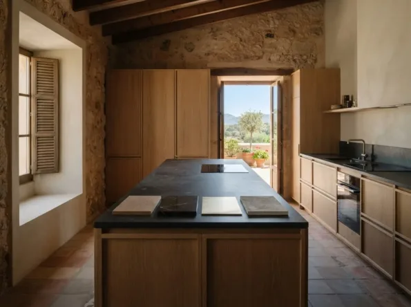 Eichenküche mit einer dunklen Steininsel und vier Materialmustern in einer Reihe darauf, eine Tür zu einer Terrasse und Hügeln