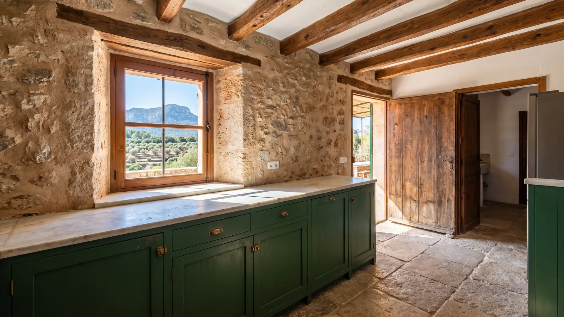 Küche mit Steinwänden und dunkelgrünen Unterschränken, Marmor-Arbeitsplatte und einem Fenster mit Blick auf terrassierte Hügel und Berge